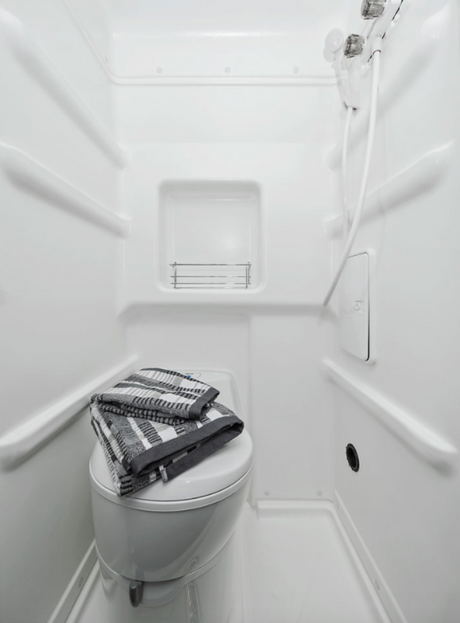 Enjoy a functional and clean RV rental wet bath, featuring a toilet, integrated shower, and storage for toiletries.