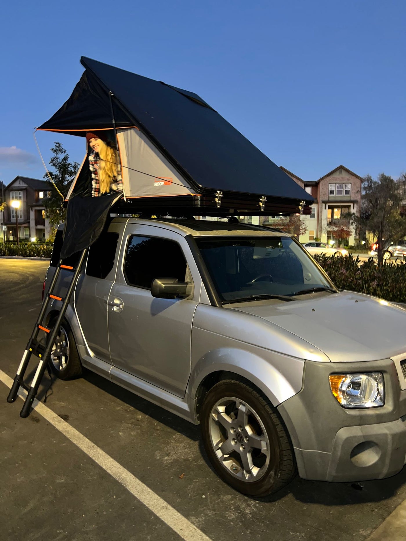 ideal for your next compact RV rental or camping adventure.|Ready for adventure! A person smiles from a rooftop tent on a silver Honda Element — photo 4