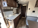 RV rental interior: full kitchen with sink, stovetop, microwave, dark wood cabinets, and dinette seating.