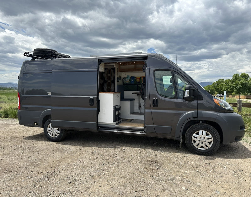 Experience outdoor living! This grey van conversion rv rental features an open side door revealing a cozy interior. — photo 3