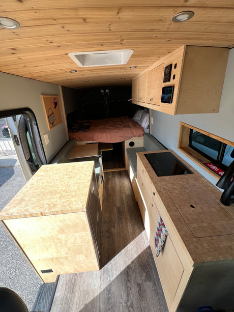 Spacious, modern camper van interior, perfect for your next RV rental adventure. Features wood accents, kitchen, and cozy bed.