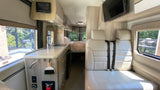 Inside this RV rental: a modern kitchen, comfortable seating with seatbelts, and a cozy rear bed. Ready for your adventure!
