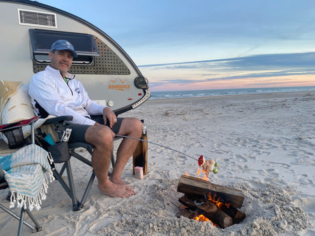 Enjoying beach camping by our RV rental, cooking dinner over a beach bonfire at sunset. A perfect, relaxing getaway!