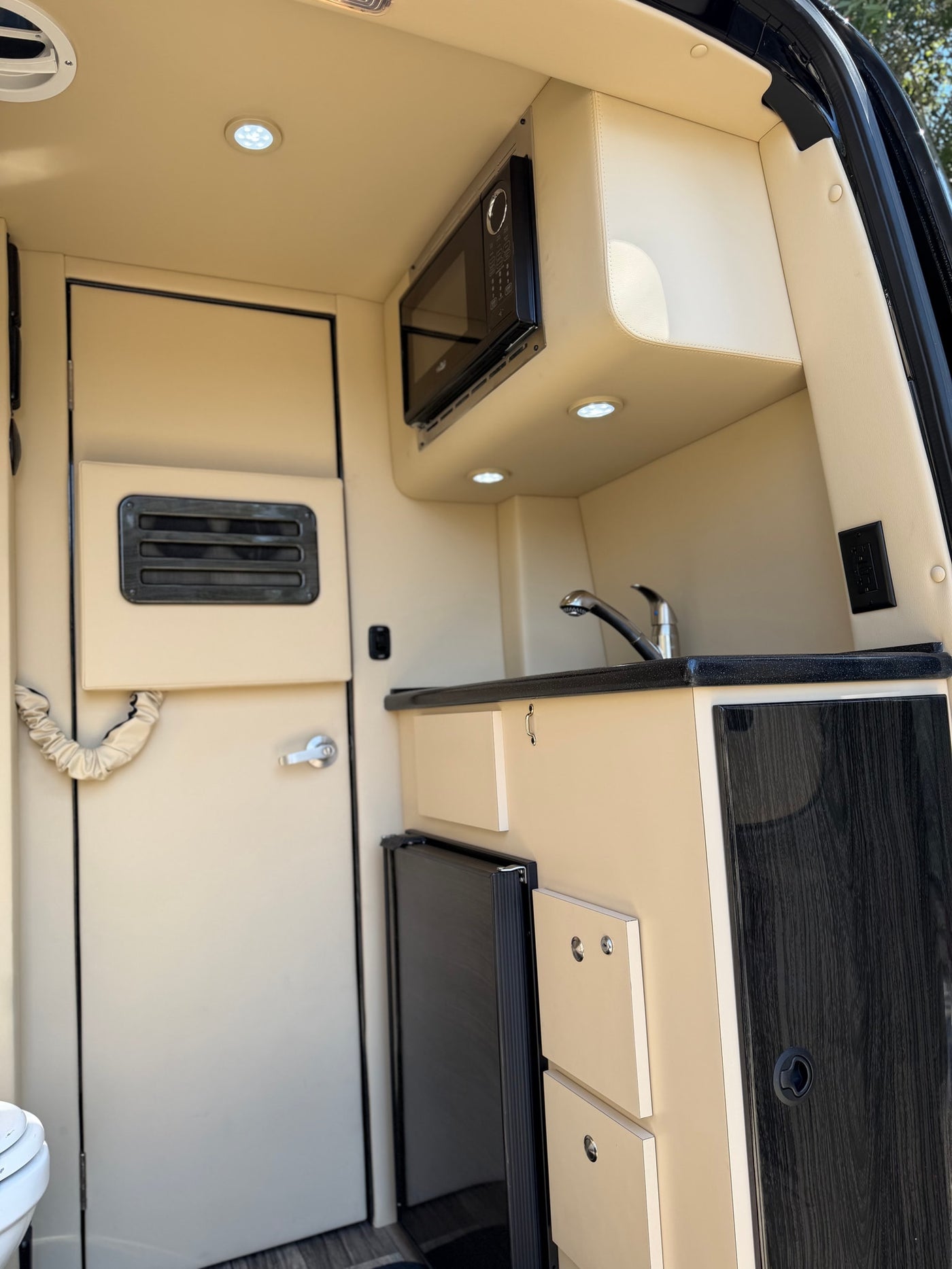 This rv rental features a well-equipped compact kitchenette with a microwave, sink, and fridge, perfect for travel convenience. — photo 5