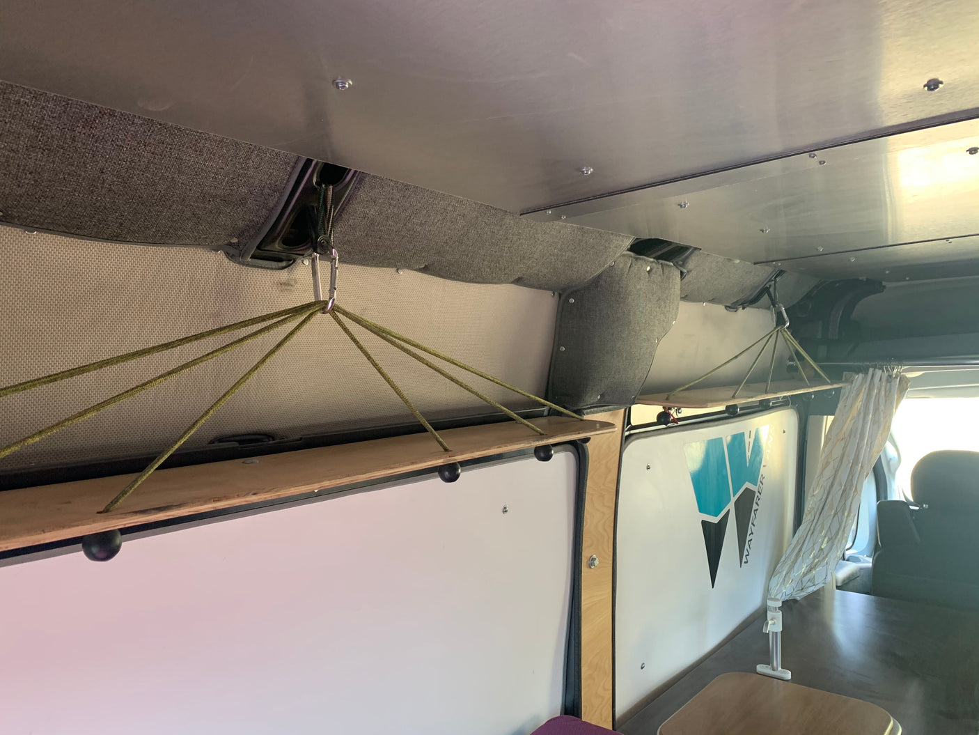 Clever hanging shelves offer storage in this Wayfarer Vans rv rental, showcasing a custom van interior.