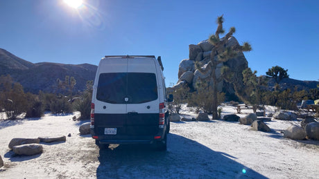 RV rental van parked in a snowy Joshua Tree campground. Perfect for winter desert camping & adventure.