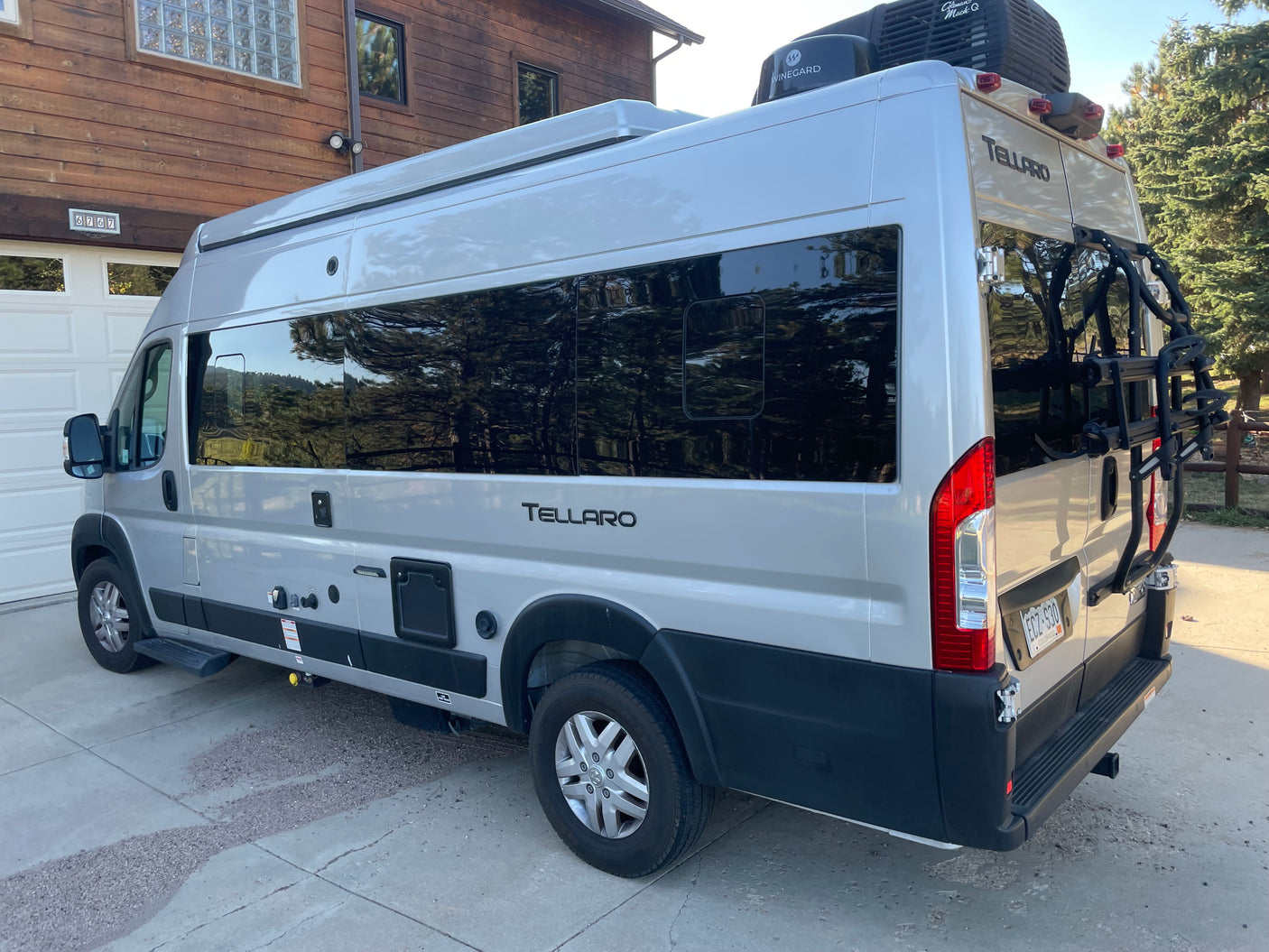 Silver Tellaro camper van RV rental parked at home, side and rear visible. Ideal for outdoor adventures.