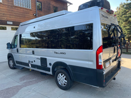 Silver Tellaro camper van RV rental parked at home, side and rear visible. Ideal for outdoor adventures.