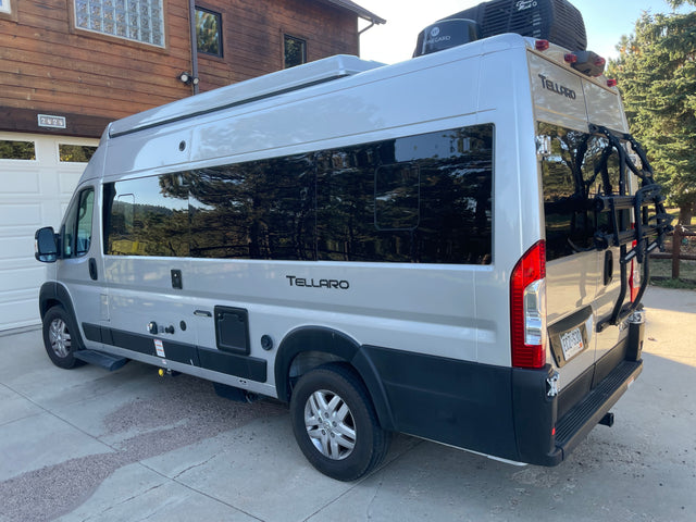 Silver Tellaro camper van RV rental parked at home, side and rear visible. Ideal for outdoor adventures.