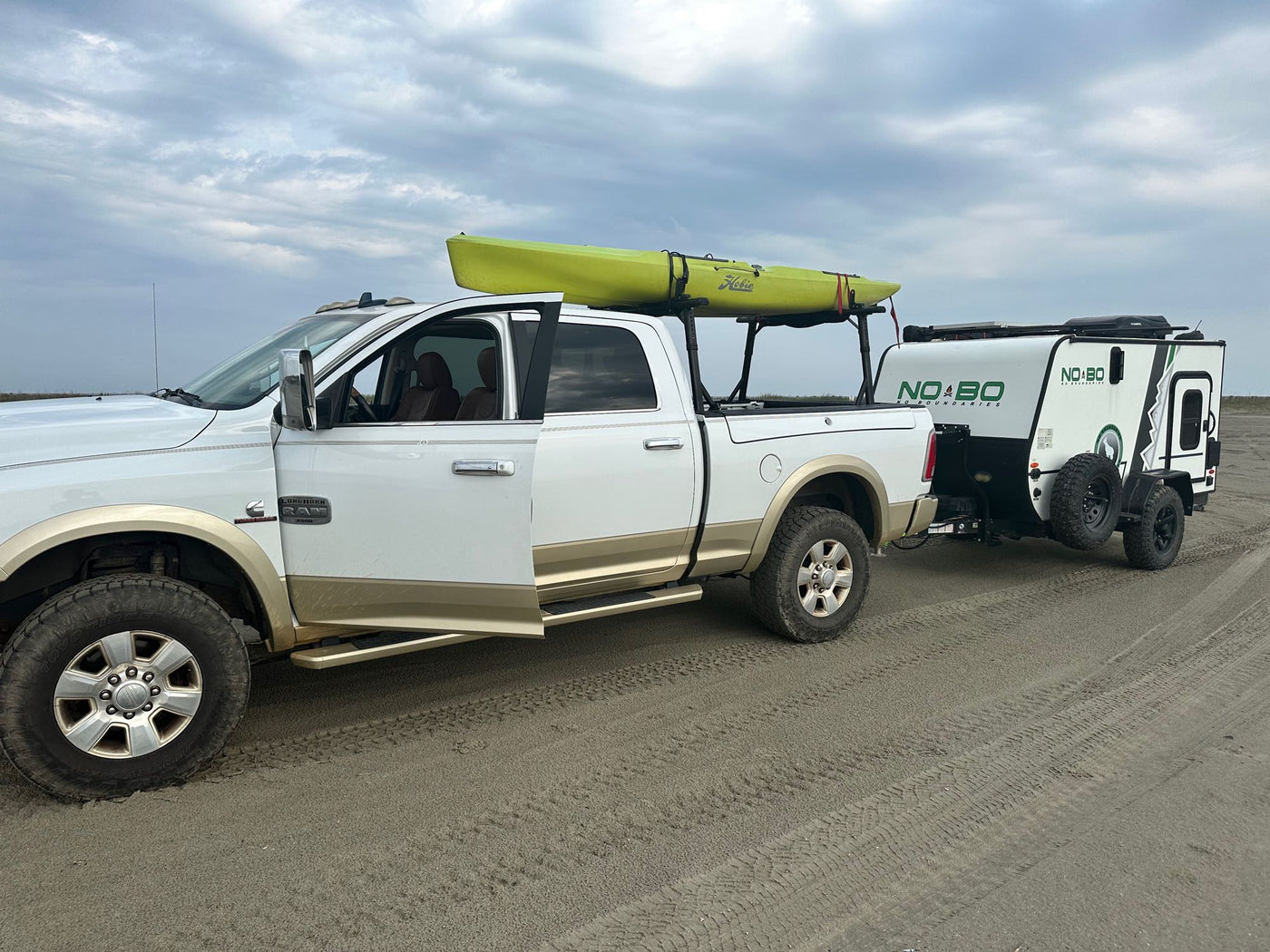 White Ram truck with kayak tows a NO BO RV on sand. — photo 13