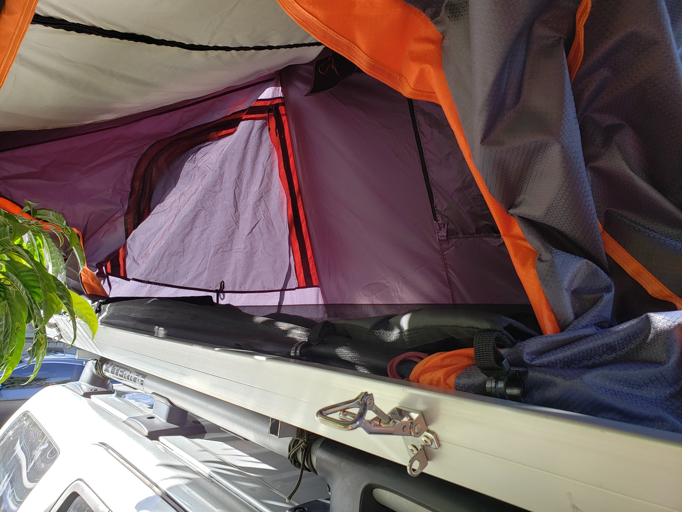 Inside a vibrant orange and purple rooftop tent on an RV rental vehicle, perfect for outdoor adventure.