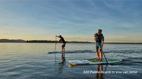 Two people paddleboarding on a calm lake. Elevate your RV rental adventure with these watersports.