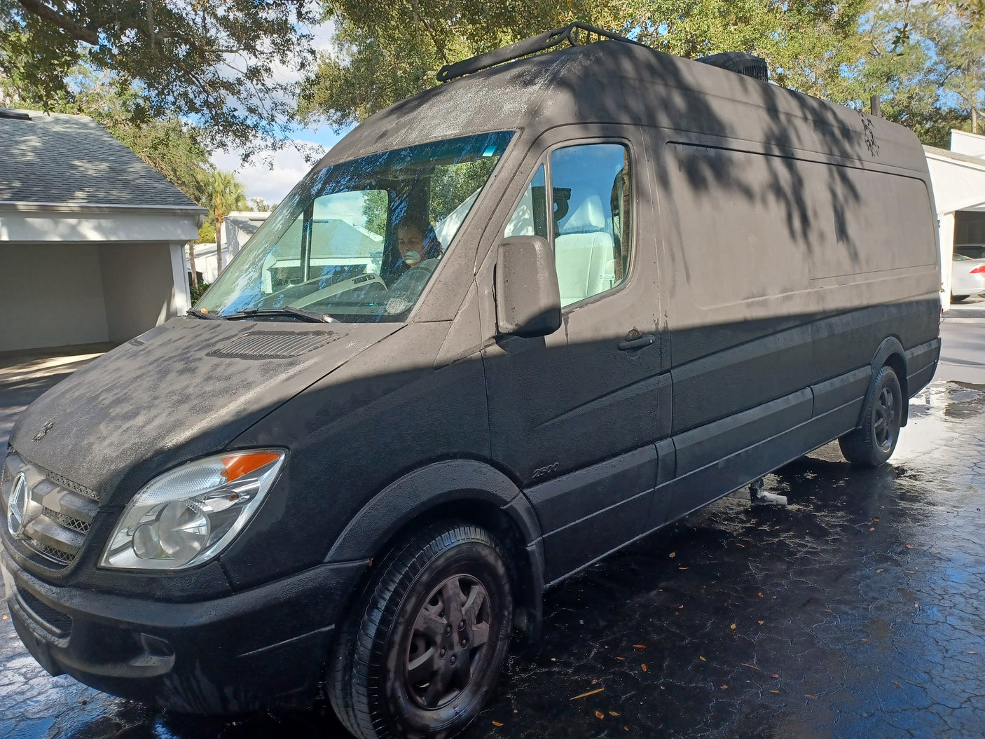 This black Mercedes Sprinter van, a custom rv rental, features a rugged textured finish and roof rack.