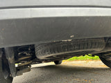 Underside view of an RV rental: spare tire mounted below, with shock absorber and coil spring visible.