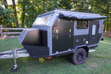 Explore off-road with this rugged RV rental! Grey/black camper trailer with awning & gear storage for outdoor adventure.