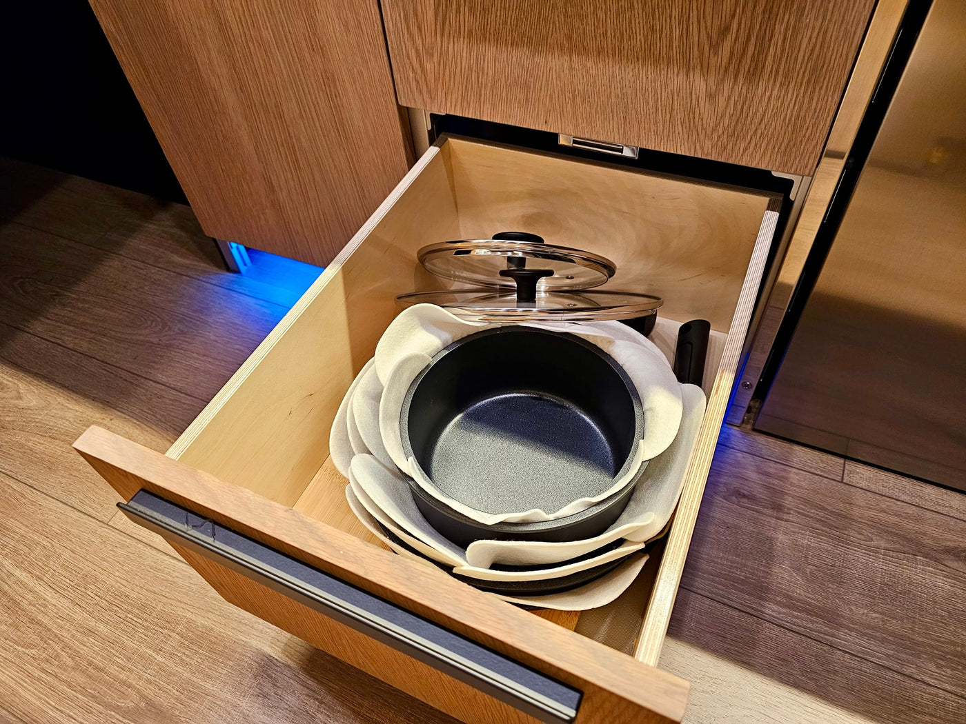 RV rental kitchen: Open drawer reveals neatly stacked pots, pans, and lids with felt protectors. Efficient storage for compact living. — photo 14