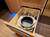 RV rental kitchen: Open drawer reveals neatly stacked pots, pans, and lids with felt protectors. Efficient storage for compact living.