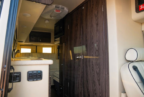 Step inside this RV rental: a modern interior with a functional kitchenette, ample dark wood storage, and rear lounge.
