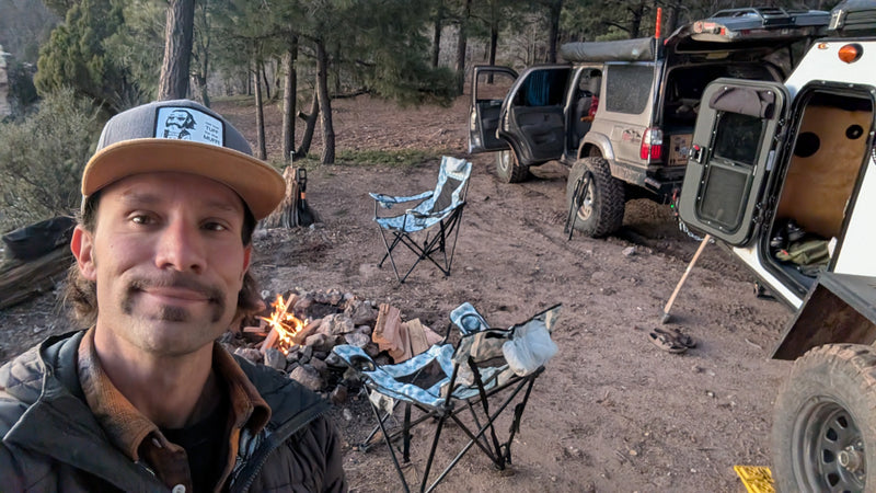 RV rental ready for adventure! Man by campfire, overlanding SUV, & trailer in a forest campsite. — photo 11