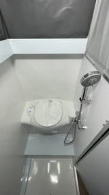 This RV rental's compact wet bath includes a toilet (covered), shower, and integrated shower pan, maximizing small space utility.