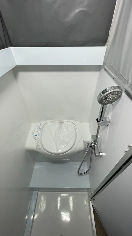 This RV rental's compact wet bath includes a toilet (covered), shower, and integrated shower pan, maximizing small space utility.