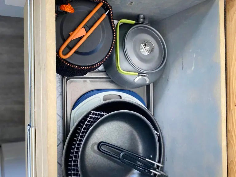Organized kitchenware in an RV rental: pots, pans, kettle, and cutting board neatly stored for your adventures. — photo 13