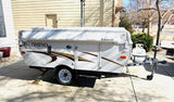 This white Palomino pop-up camper, great for RV rental, parked on a sunny driveway. Equipped with a Dometic awning and propane tank.