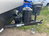 RV rental ready for adventure! Front view of trailer with propane tanks, battery, and hitch. Great for camping trips.