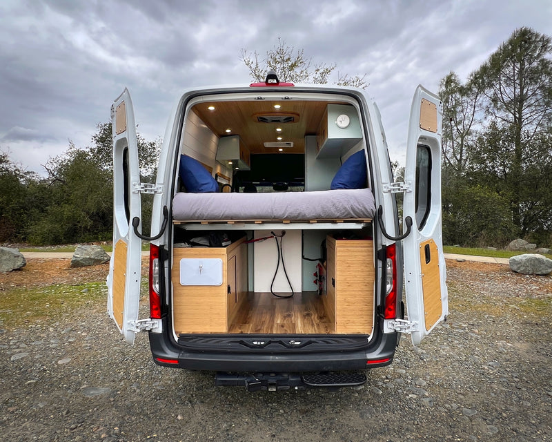  and wood counter. View outside features trees and rocks.|RV rental: Modern kitchen with open pull-out Isotherm fridge — photo 19