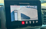 An RV rental van's 360-degree camera aids parking, showing top and rear views of the RV lot for safe maneuvering.