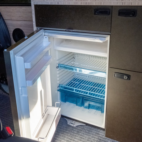 rv rental: an open, compact refrigerator with clean shelves & blue crisper drawers, ready for your road trip adventure.