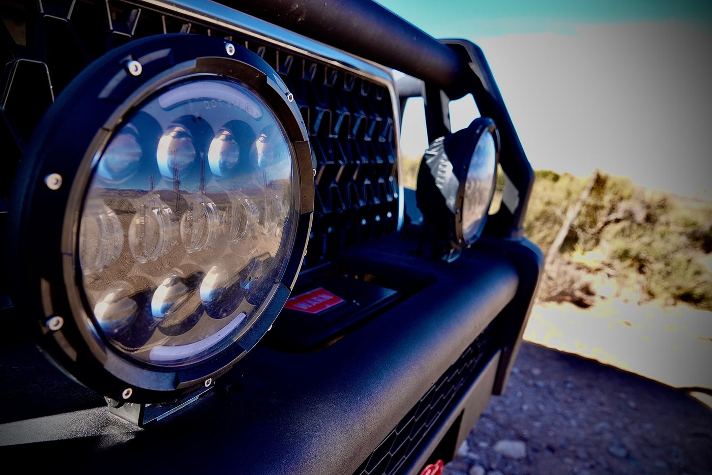 Detail of an RV rental off-road vehicle's LED light, reflecting a desert landscape and utility poles. — photo 13