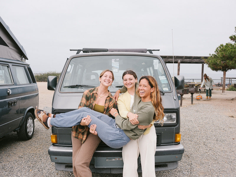 Three smiling friends pose playfully in front of their camper van. An RV rental adventure by the sea awaits! — photo 6