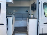 Modern rv rental interior: compact kitchen, cozy dinette, microwave, & TV. Perfect for adventurous travel.