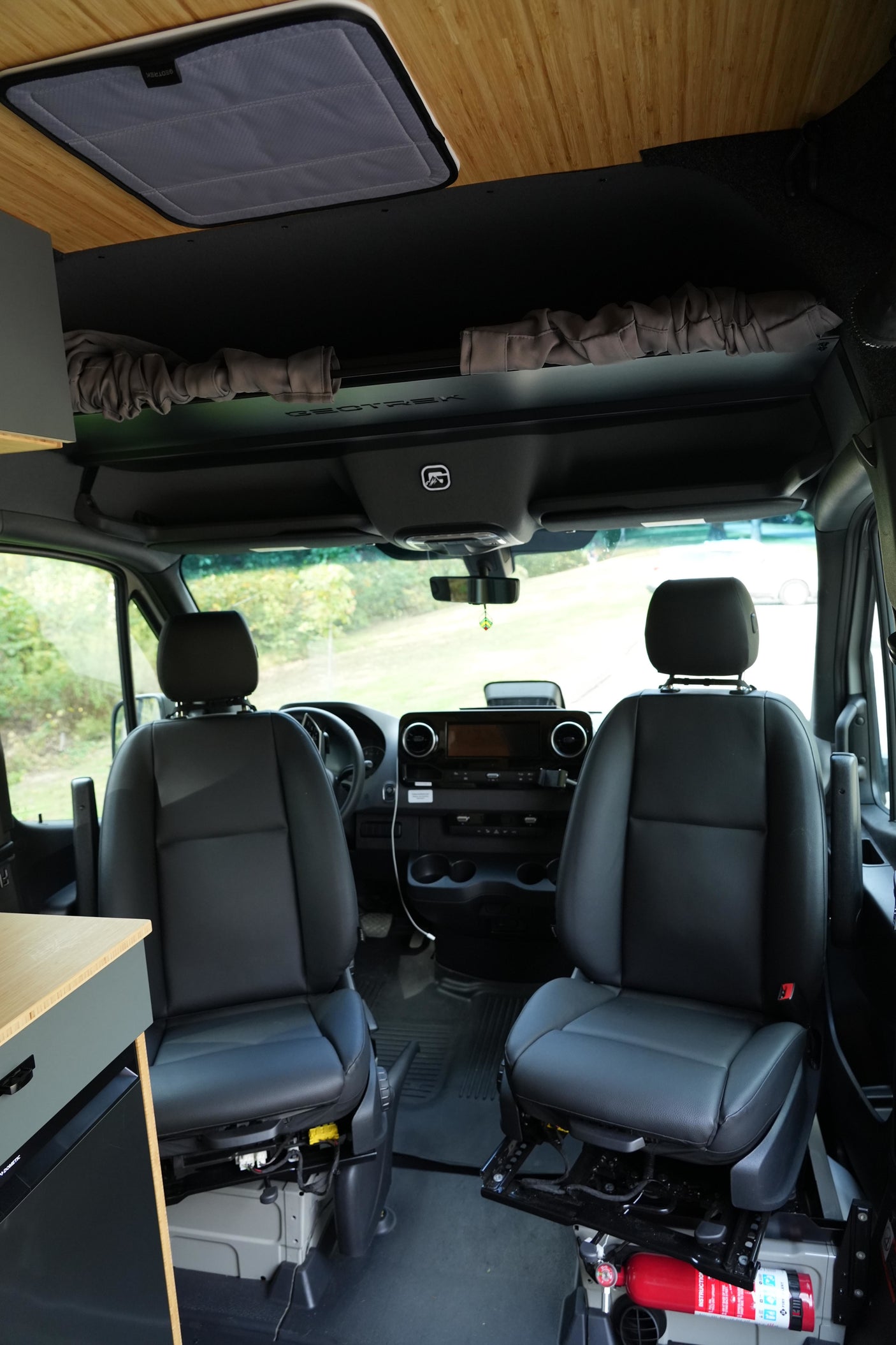 RV rental van's front cabin: black seats, detailed dashboard, and custom wood ceiling. Ready for road trips.
