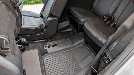 RV rental interior with black leather rear seats and durable, all-weather floor mats for comfortable journeys.