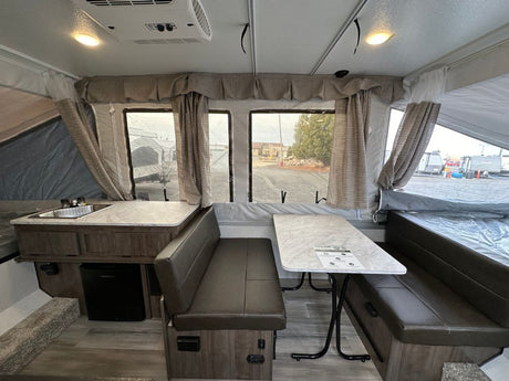 Pop-up rv rental interior: compact living space with kitchenette (sink, fridge), dinette, and bed. Perfect for adventurers!