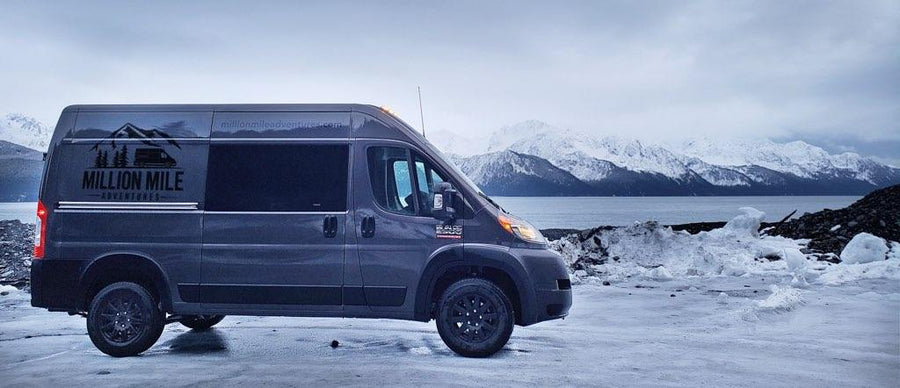Million Mile Adventures RV rental van on icy shore, with snow-capped mountains across water. Your adventure starts!