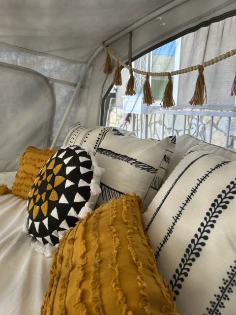 Cozy interior of an RV rental with stylish pillows and decorative tassels by the window. Perfect for a comfortable road trip. — photo 13