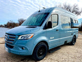 Light blue Xalta Mercedes-Benz Sprinter RV rental parked lakeside. Perfect for outdoor adventures!