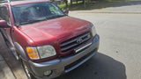 A dusty red Toyota Sequoia SUV, equipped with auxiliary lights, parked on asphalt. Great for adventures, no rv rental needed.