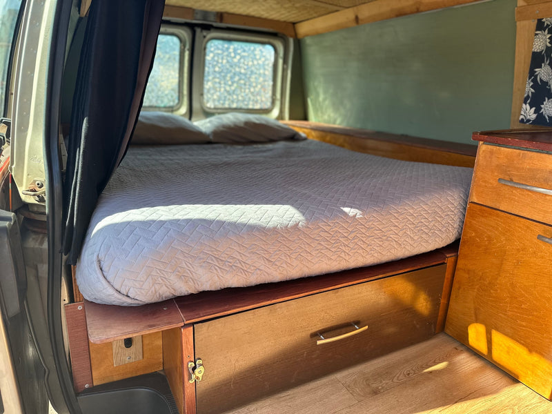Experience an RV rental: cozy campervan interior featuring a comfy bed, wood accents, and practical storage solutions. — photo 9