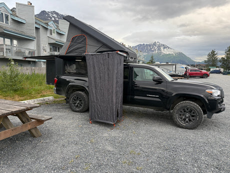 This overland Tacoma rv rental features a rooftop tent & privacy shower, ideal for camping with mountain scenery.