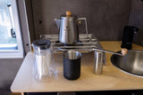 RV rental kitchen with portable coffee gear: Snow Peak kettle, grinder, Fellow carafe, and sink for fresh brews on the go.