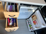 Organized rv rental kitchen with open drawers & stocked mini-fridge, showing efficient storage for travel essentials.