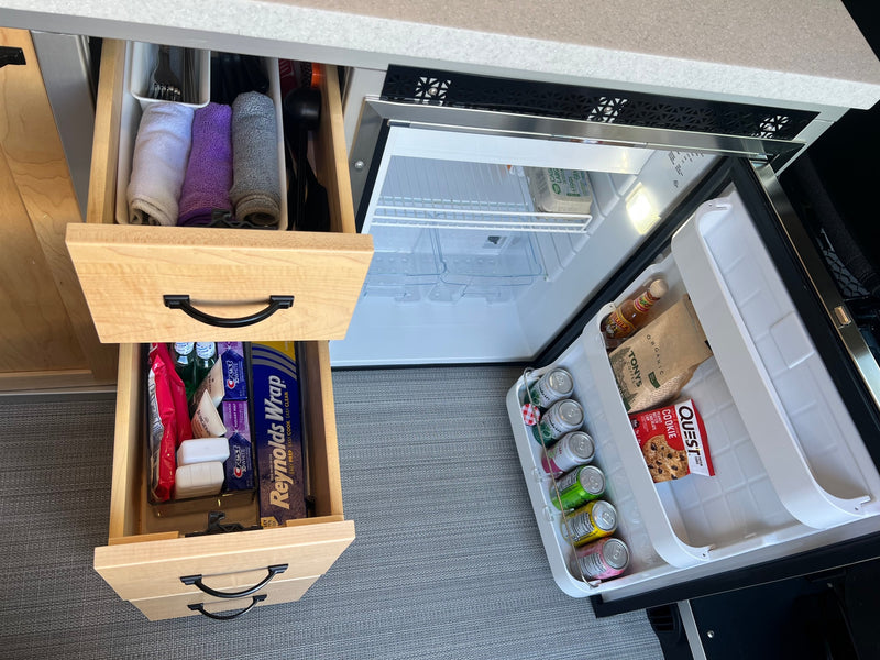 Organized rv rental kitchen with open drawers & stocked mini-fridge, showing efficient storage for travel essentials. — photo 14