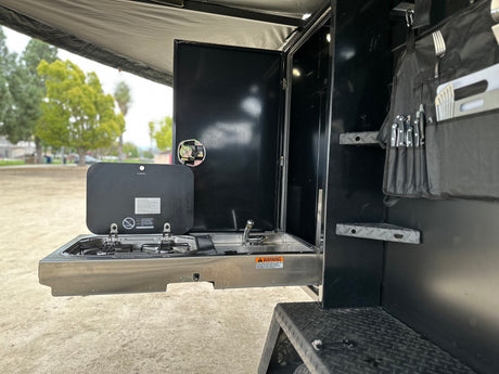 This RV rental features a pull-out Dometic outdoor kitchen with stove, sink, and utensil storage, ideal for camping.