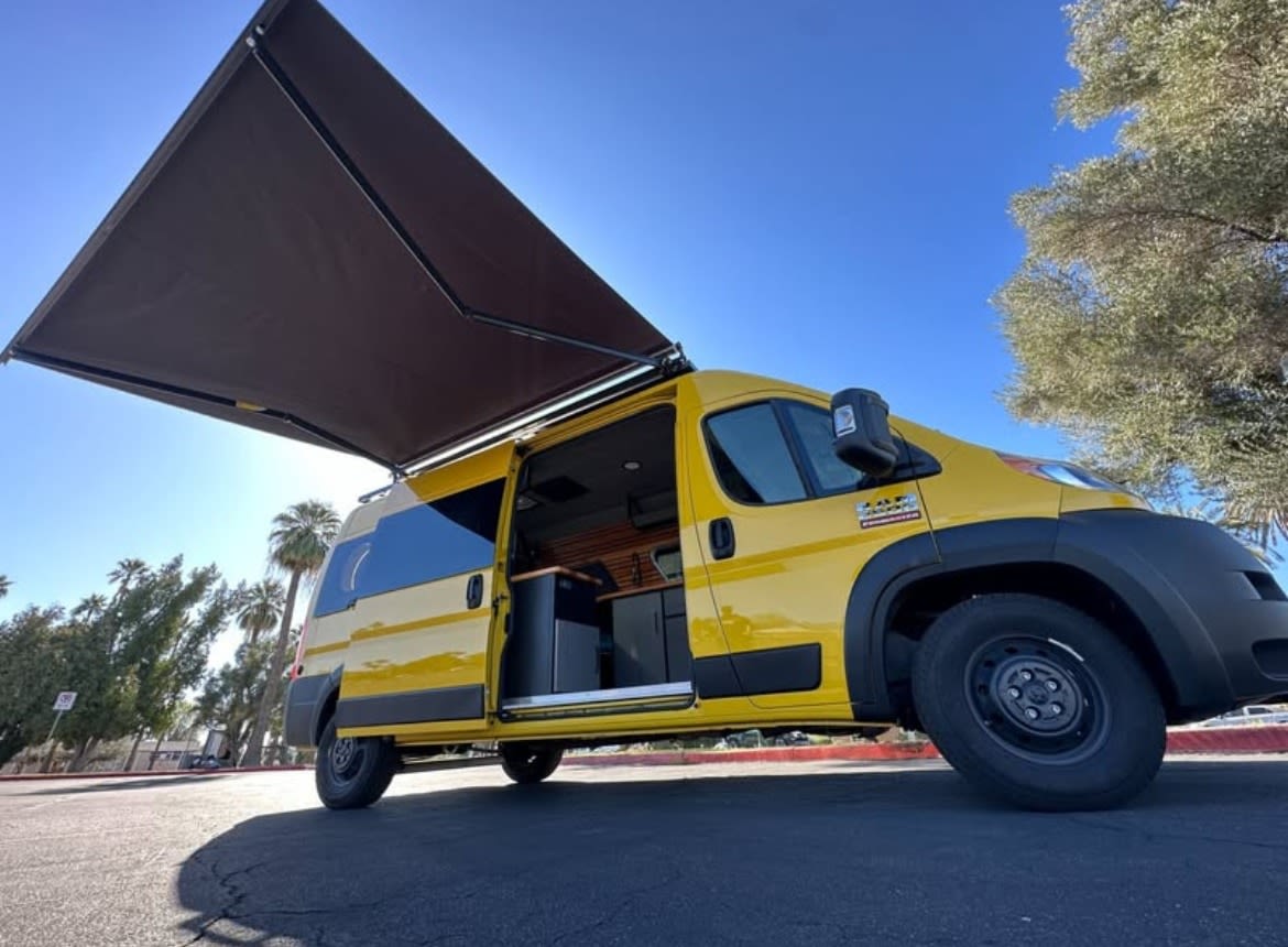 Yellow camper van with extended awning, side door open, under a blue sky. This RV rental is ready for your travel adventures. — photo 2