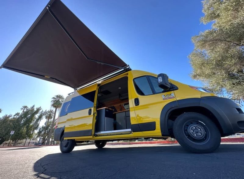 Yellow camper van with extended awning, side door open, under a blue sky. This RV rental is ready for your travel adventures. — photo 2