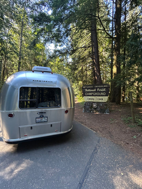 A silver Airstream RV rental parked at the Mt. Baker-Snoqualmie National Forest Campground entrance, Denny Creek, Washington.